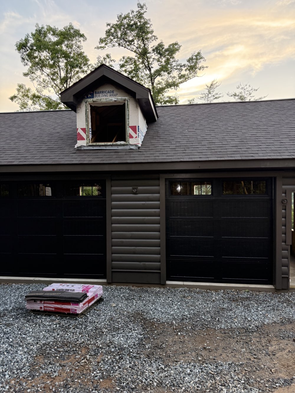 Two black carriage-style garage doors on a rustic detached garage in the Upstate SC