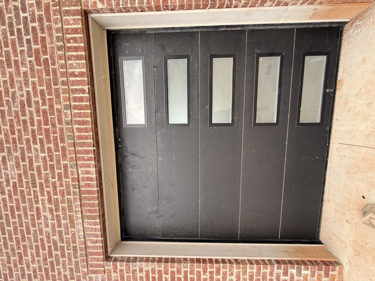 Black modern garage door with vertical side window column on a brick home in Spartanburg SC