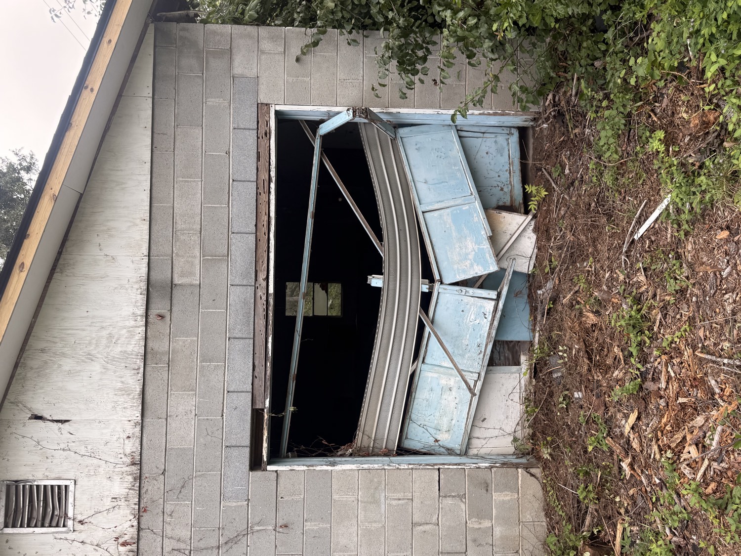 Before: an old garage door buckled and collapsed in the opening of a cinder-block garage