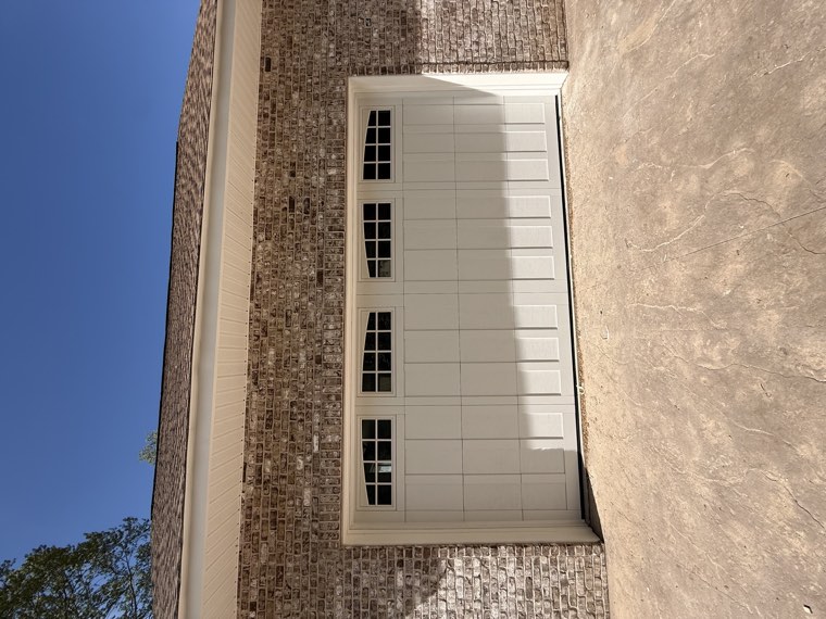 Almond carriage-house garage door with arched window inserts on a brick ranch home in Spartanburg, SC