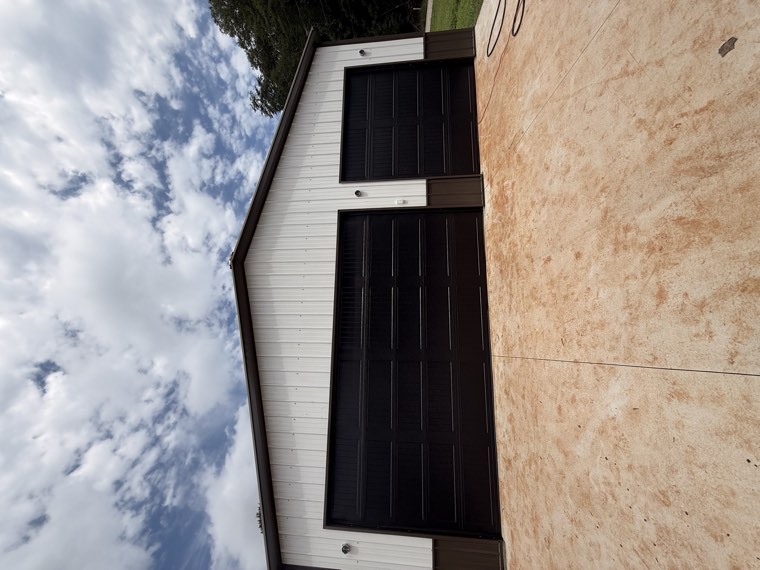 White pole barn with a double and a single black garage door installed by Viking Garage Door