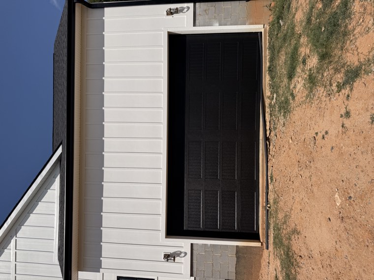 Black long-panel garage door installed on a new white board-and-batten farmhouse in Spartanburg, SC
