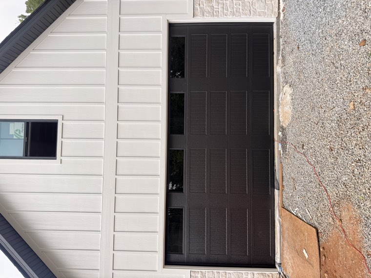 Dark bronze long-panel garage door with top windows on a board-and-batten and stone home in the Upstate SC