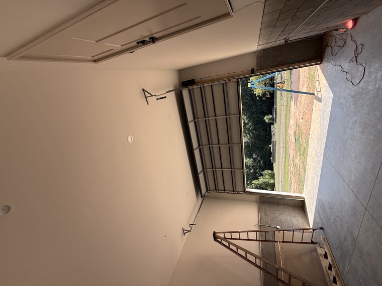 Tall commercial garage door partly installed inside a new building with a ladder in place