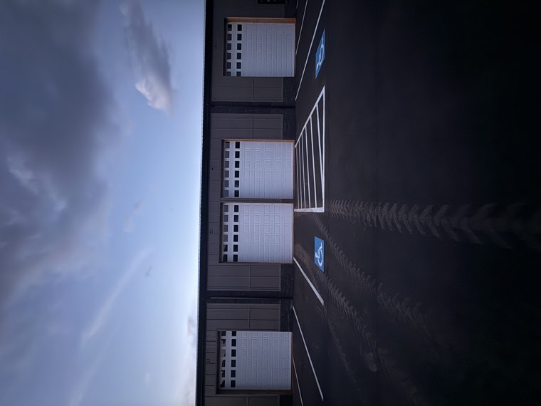 Four white commercial garage doors on a contractor building at dusk in the Upstate SC