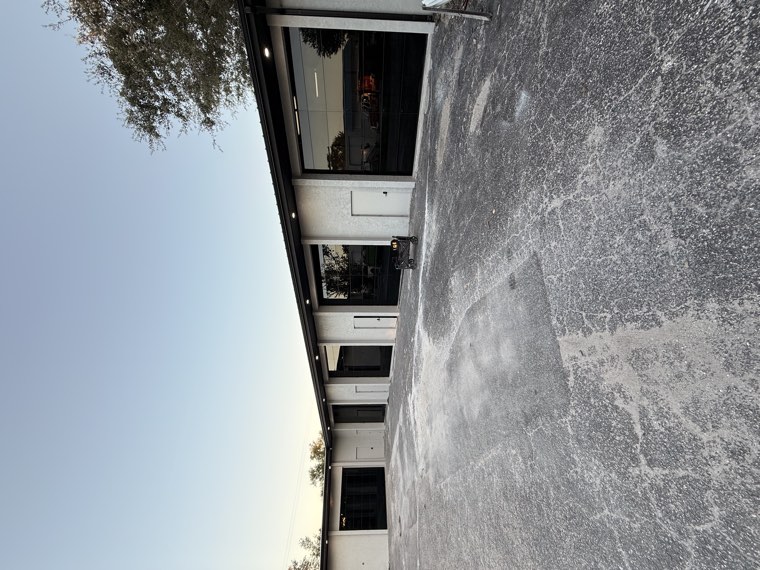 Commercial building with a row of black full-view glass garage doors at dusk