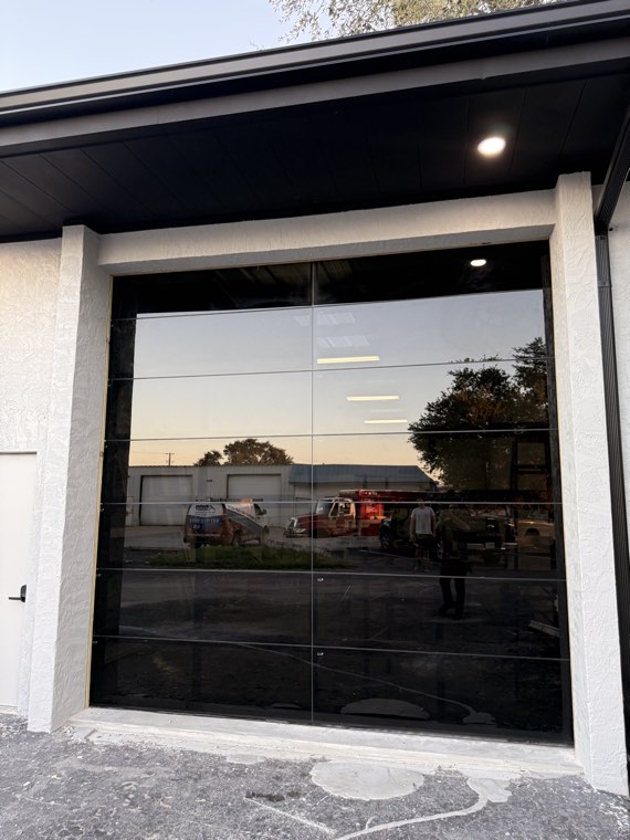 Black aluminum full-view glass garage door installed on a commercial building