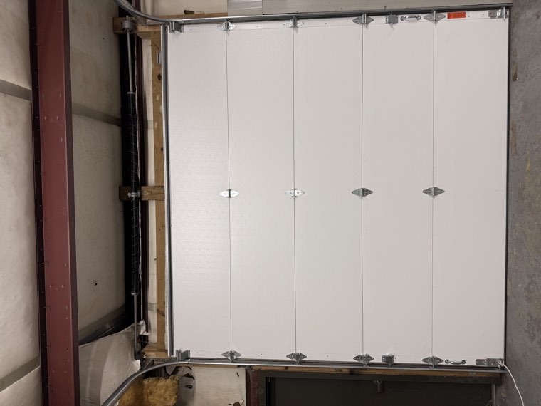 Interior view of a new white insulated commercial door with heavy-duty track and hardware