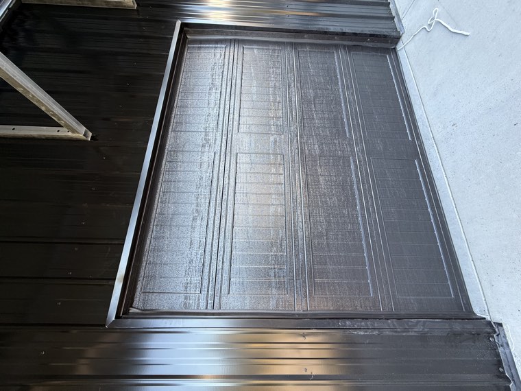 Angled view of a dark woodgrain overhead door in a black metal shop building in the Upstate SC