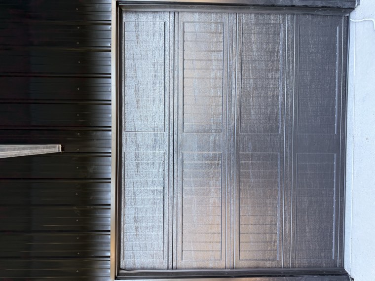 Dark woodgrain commercial garage door installed in a black metal shop building