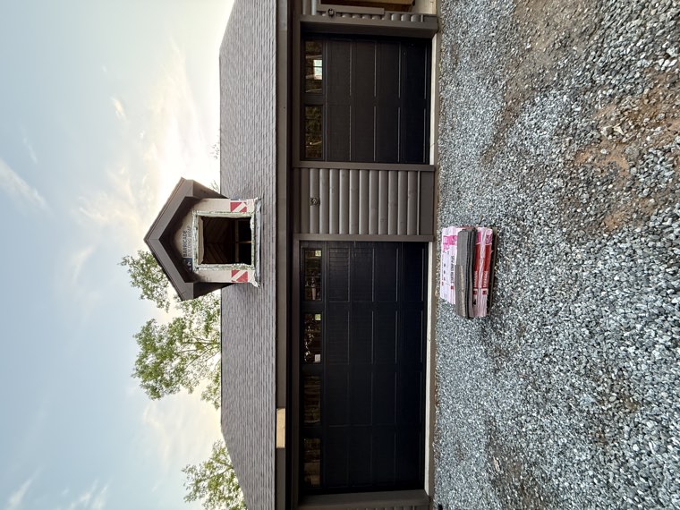 Front view of a detached three-car garage with dark brown carriage-house garage doors installed by Viking