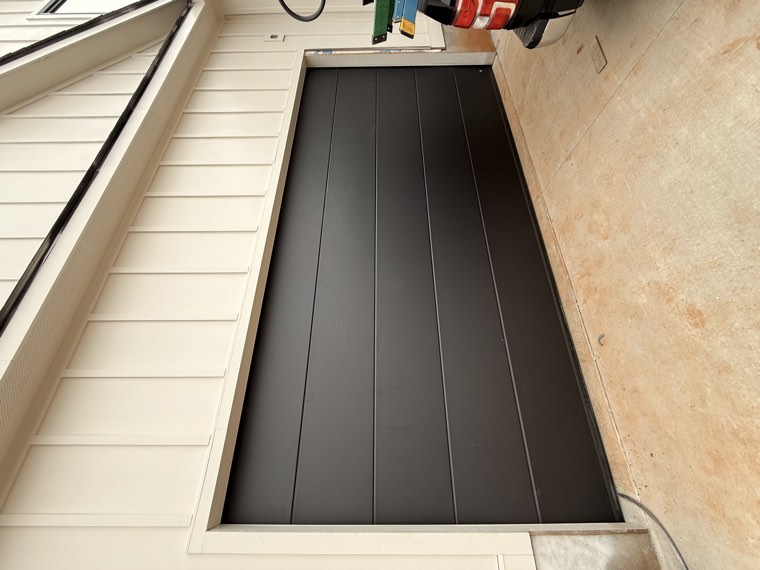 Matte black modern flush garage door installed on a white board-and-batten farmhouse in Boiling Springs, SC