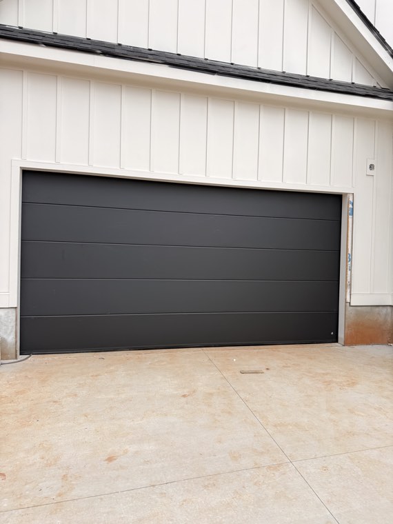Black flush-panel double garage door on a white farmhouse garage near Spartanburg, SC