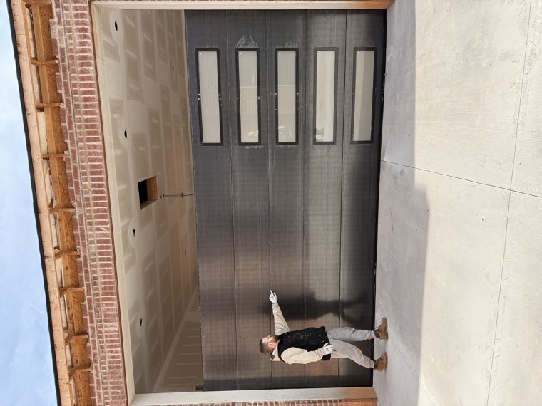 Viking Garage Door technician beside a newly installed bronze modern garage door with a frosted window column on a brick home