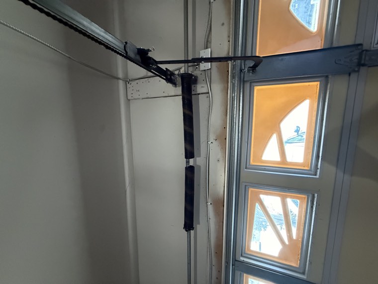 Torsion spring, shaft and opener rail above a garage door seen from inside the garage