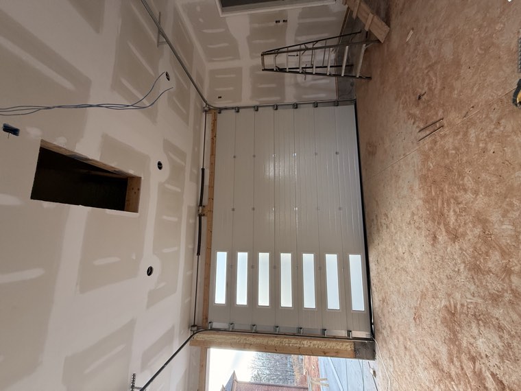 Interior view of a white garage door with a vertical column of windows in a home under construction
