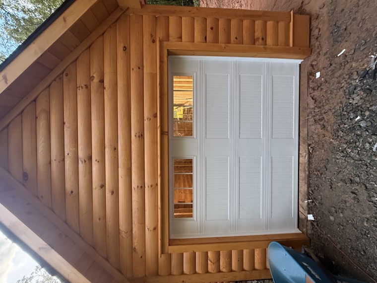 White short-panel garage door with window inserts installed on a log cabin garage in the Upstate SC