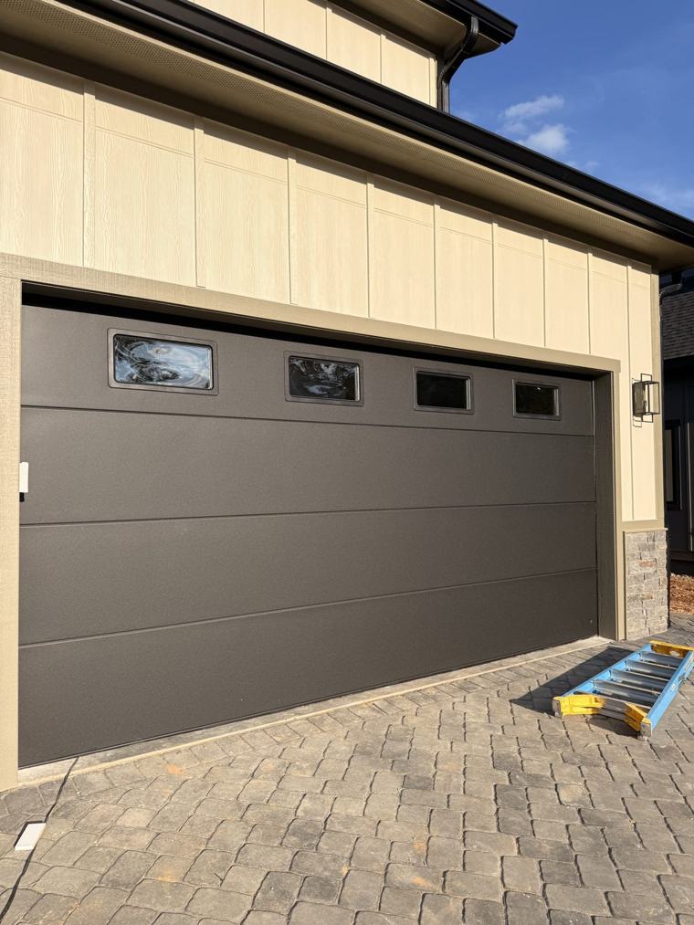 Matte black flush double door with windows over a paver driveway — installed by Viking Garage Door, Upstate SC