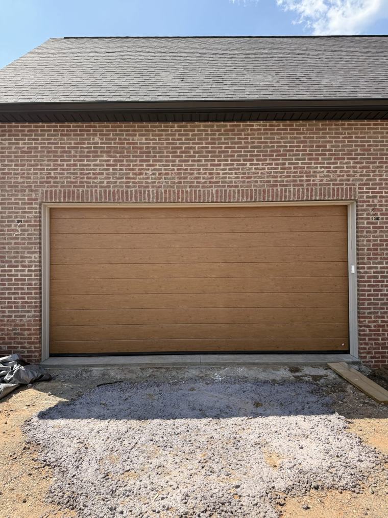 Golden-oak woodgrain flush steel garage door on a brick home — installed by Viking Garage Door, Upstate SC