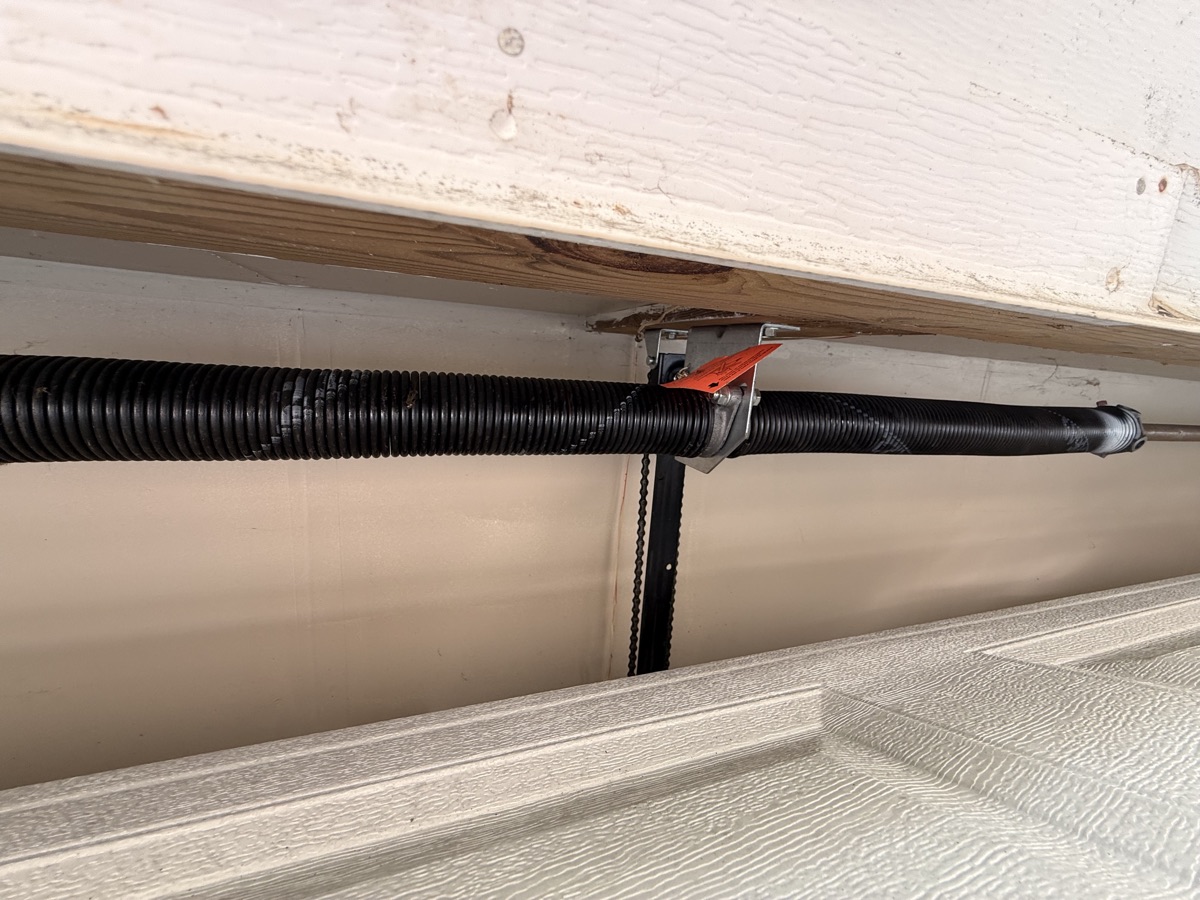 New black torsion spring installed above a garage door by Viking Garage Door in Spartanburg SC